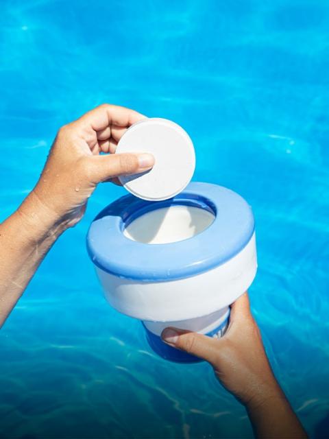 Pouring pool chemicals into a pool