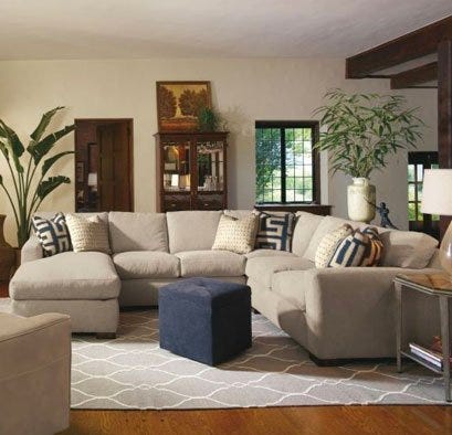 Beige cloth sectional with blue ottoman and grey rug