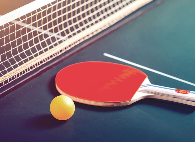 Ping pong paddle and ball on a green table